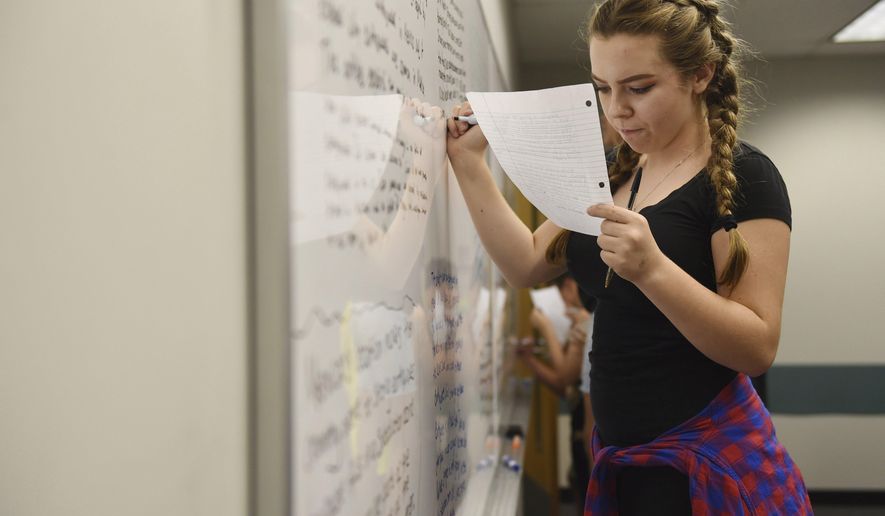 In this Friday, Sept. 22, 2017 photo, a student works at the white board during ninth grade English class in Porter Building at Eastern Michigan University, near Ann Arbor, Mich. The Early College Alliance at EMU has expanded to include a new ninth grade academy this school year. (Melanie Maxwell /The Ann Arbor News via AP)