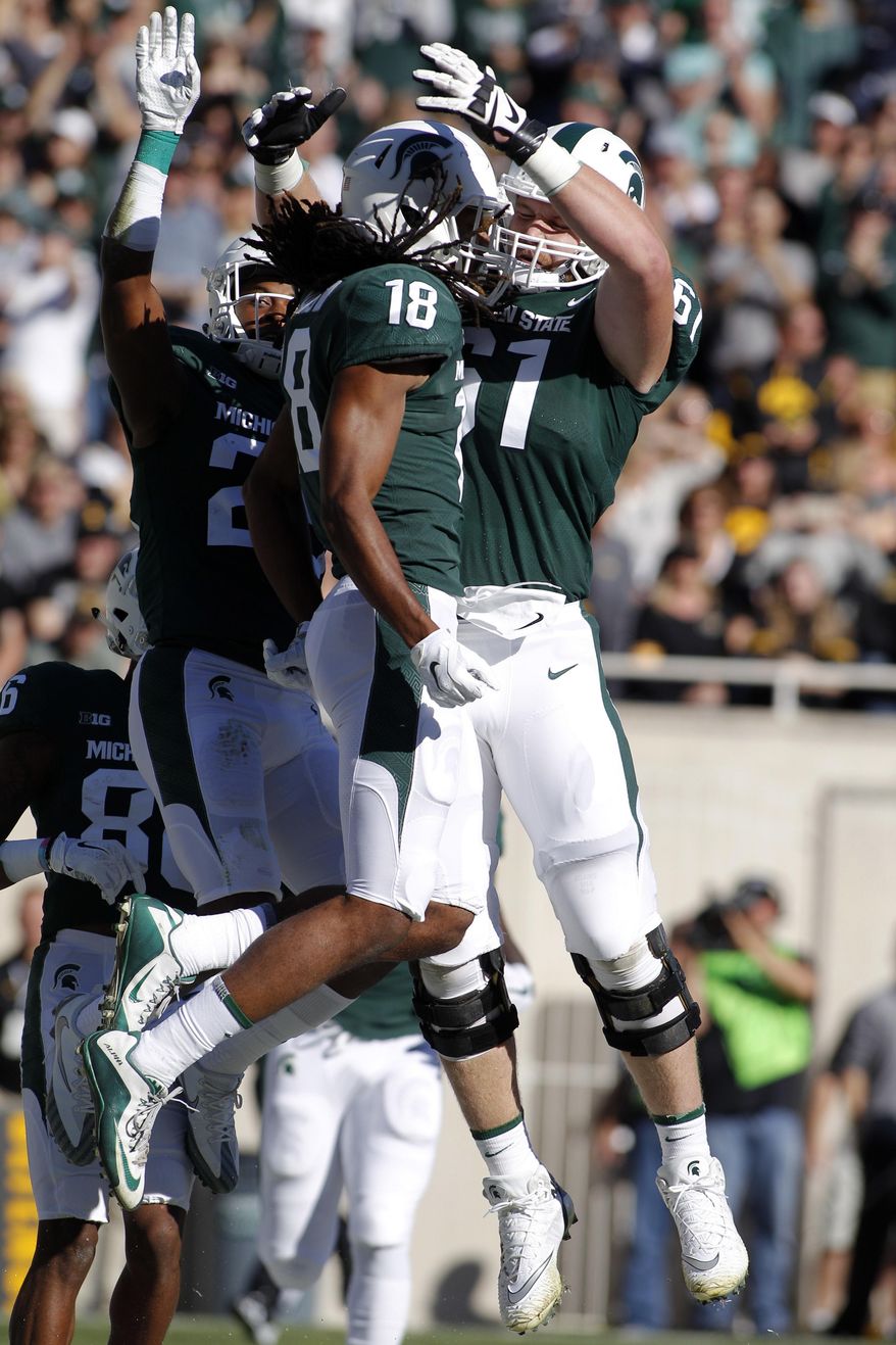 Michigan State's Felton Davis III, center, Cole Chewins, right, and Darryl Stewart, left, celebrate Davis' touchdown reception against Iowa during the first half of an NCAA college football game, Saturday, Sept. 30, 2017, in East Lansing, Mich. (AP Photo/Al Goldis)