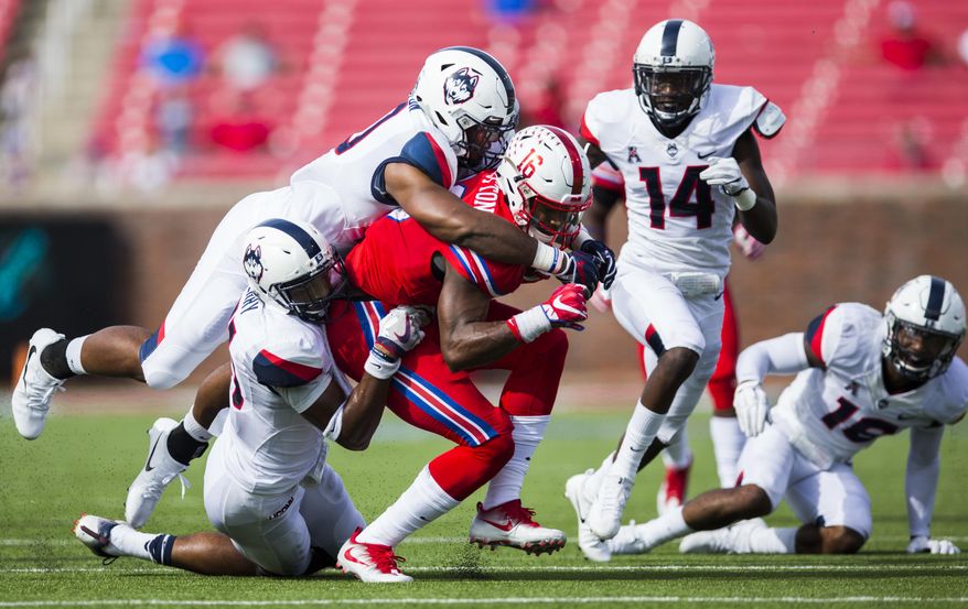 SMU wide receiver Courtland Sutton (16) is tackled by Connecticut defensive back Marshe Terry (41) and Connecticut defensive back Brice McAllister (16) during the second quarter of an NCAA college football game Saturday, Sept. 30, 2017, in Dallas. (Ashley Landis/The Dallas Morning News via AP)