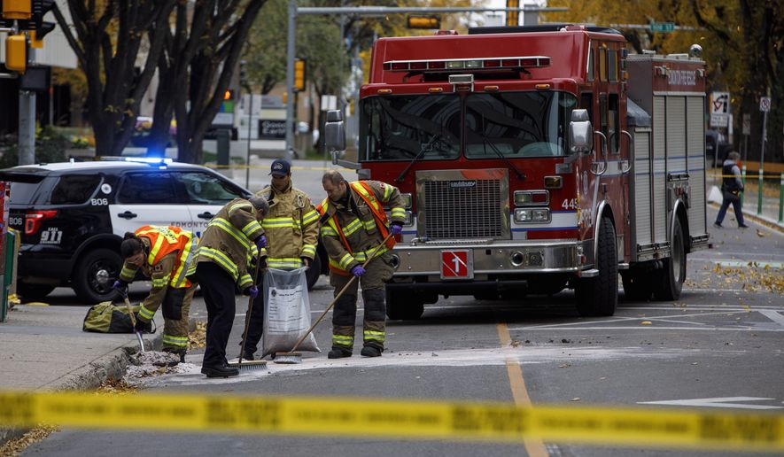 Crews clean up the scene where a van ran into pedestrians and later flipped over Saturday while being pursued by police, in Edmonton Alta, on Sunday, Oct. 1, 2017. The car and knife attack on a police officer outside a football game and a high-speed chase of a moving van that left four people injured appear to be the work of a single suspected terrorist, Canadian authorities said Sunday.(Jason Franson/The Canadian Press via AP)