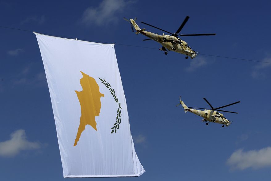 Russian-made military helicopters of the Cypriot air forces fly by a Cyprus' flag during a military parade marking the 57 years celebrations of independence, in Nicosia, in the divided island of Cyprus, Sunday, Oct. 1, 2017. The island of Cyprus has been divided since 1974, when Turkey invaded in response to a coup aimed at uniting the island with Greece. Cyprus gained independence from Britain in 1960.(AP Photo/Petros Karadjias)