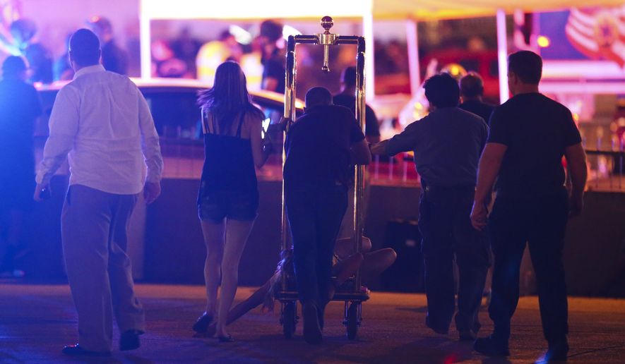 A wounded woman is moved outside the Tropicana during an active shooter situation on the Las Vegas Strip in Las Vegas Sunday, Oct. 1, 2017. Multiple victims were being transported to hospitals after a shooting late Sunday at a music festival on the Las Vegas Strip. (Chase Stevens/Las Vegas Review-Journal via AP)