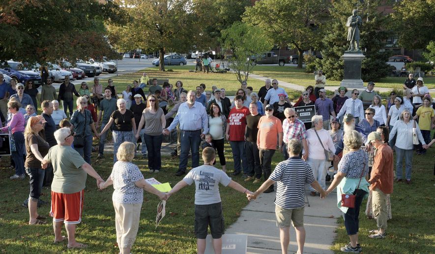 FILE - In this Sept. 12, 2017, file photo, a chorus of "We Shall Overcome" rises from a gathering against racism in Broad Street Park in Claremont, N.H. The demonstration was inspired by violence in August against an 8-year-old biracial boy that occurred while he played with a group of teenagers outside his home. The incident has prompted people in the town to reflect and assess how it handles the issue of race in this mostly white community. (James M. Patterson/The Valley News via AP, File)