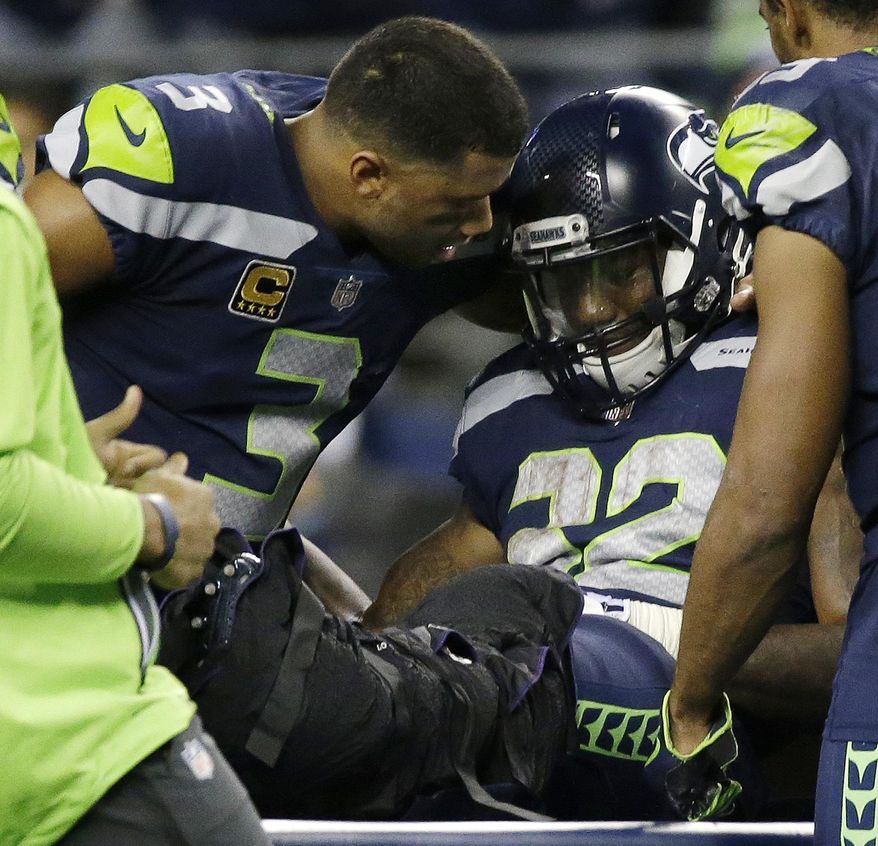 Seattle Seahawks quarterback Russell Wilson, left, comforts running back Chris Carson before Carson is taken away on a cart after suffering an injury in the second half of an NFL football game against the Indianapolis Colts, Sunday, Oct. 1, 2017, in Seattle. (AP Photo/Elaine Thompson)