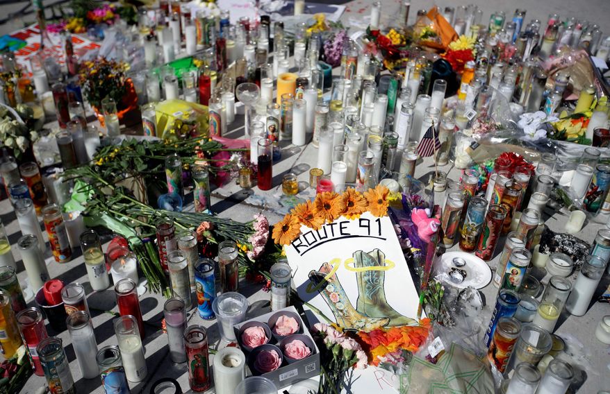 Flowers and candles are left at a makeshift memorial site on Las Vegas Boulevard on Tuesday, Oct. 3, 2017, in Las Vegas. A gunman opened fire on an outdoor music concert on Sunday killing dozens and injuring hundreds. (AP Photo/Chris Carlson)