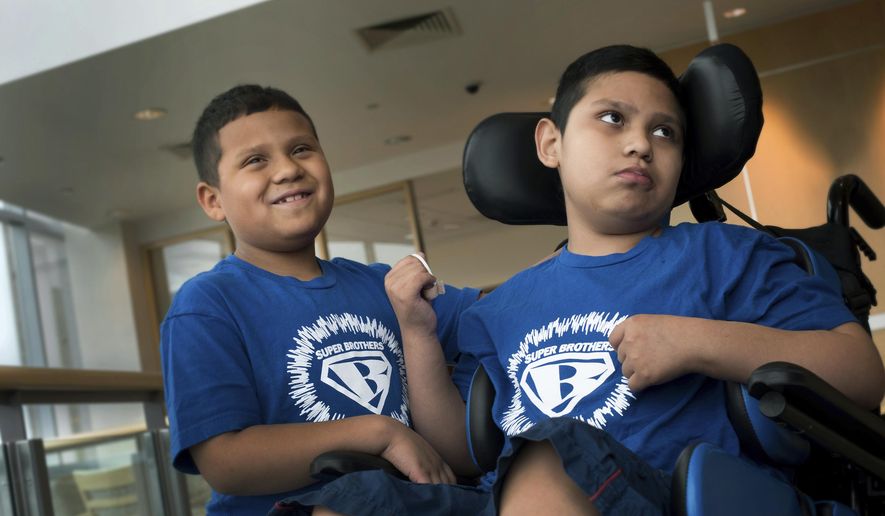In this Aug. 29, 2017 photo provided by Boston Children’s Hospital, Brian Rojas smiles while standing next to his brother Brandon at Boston Children's Hospital. The boys suffer from adrenoleukodystrophy, an inherited nerve disease featured in the movie "Lorenzo's Oil." Brian was able to benefit from an experimental treatment while the disease had progressed too far in Brandon to qualify for the gene therapy study. Study results were published Wednesday, Oct. 4 by the New England Journal of Medicine and discussed at the Child Neurology Society conference in Kansas City. (Katherine C. Cohen/Boston Children’s Hospital via AP)