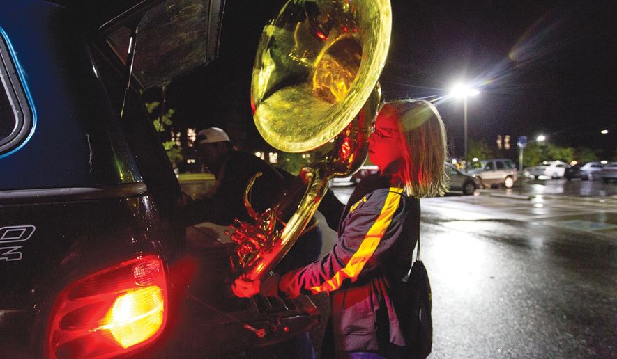 In this Sept. 22, 2017, photo, University of Wyoming student Amanada Johnston loads her sousaphone into the back of a pickup truck in the Buchanan Center's parking lot in Laramie, Wyo. The band carpools from the center to the bars. (Shannon Broderick/Laramie Daily Boomerang via AP)