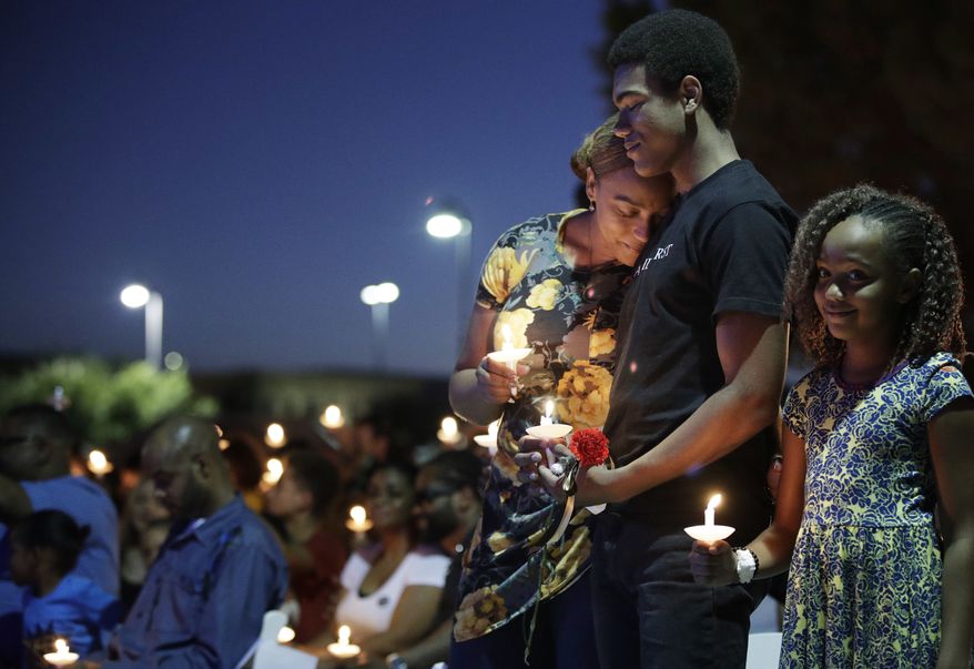 From left, Veronica Hartfield, wife of Las Vegas police officer Charleston Hartfield, embraces son Ayzayah Hartfield beside daughter Savannah Hartfield during a candlelight memorial for the officer, Thursday, Oct. 5, 2017, in Las Vegas. Hartfield was killed when Stephen Craig Paddock broke windows on the Mandalay Bay resort and casino and began firing with a cache of weapons at a country music festival Sunday. Dozens of people were killed and hundred were injured. (AP Photo/John Locher)