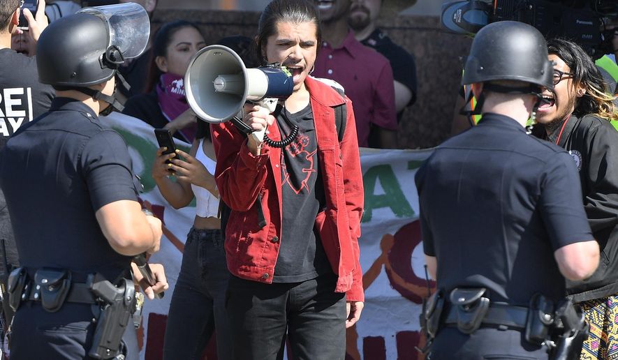 A protestor shouts at cops with a bullhorn on Wilshire Boulevard, outside the Federal Building in Westwood, Calif., as DACA supporters square off with LAPD on deadline day for DACA renewals Thursday, Oct. 5, 2017. ( John McCoy/Los Angeles Daily News via AP)