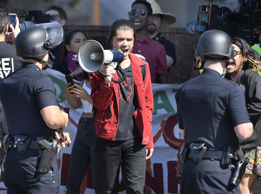 A protestor shouts at cops with a bullhorn on Wilshire Boulevard, outside the Federal Building in Westwood, Calif., as DACA supporters square off with LAPD on deadline day for DACA renewals Thursday, Oct. 5, 2017. ( John McCoy/Los Angeles Daily News via AP)