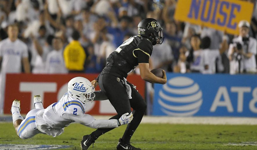Colorado quarterback Steven Montez, right, escapes a tackle by UCLA linebacker Josh Woods during the second half of an NCAA college football game, Saturday, Sept. 30, 2017, in Pasadena, Calif. UCLA won 27-23. (AP Photo/Mark J. Terrill)