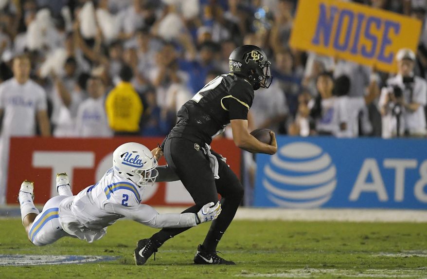 Colorado quarterback Steven Montez, right, escapes a tackle by UCLA linebacker Josh Woods during the second half of an NCAA college football game, Saturday, Sept. 30, 2017, in Pasadena, Calif. UCLA won 27-23. (AP Photo/Mark J. Terrill)