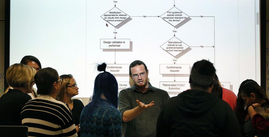 In this Monday, Oct. 2, 2017 photo, teacher Kevin R. Buckingham shows medical equipment to single moms in poverty who are in the Invest in You Too program at Salt Lake Community College in Sandy, Utah. The Department of Workforce Services' program is a 13-week course that helps single mothers build skills in medical manufacturing and job readiness to open doors for employment. (Ravell Call/The Deseret News via AP)