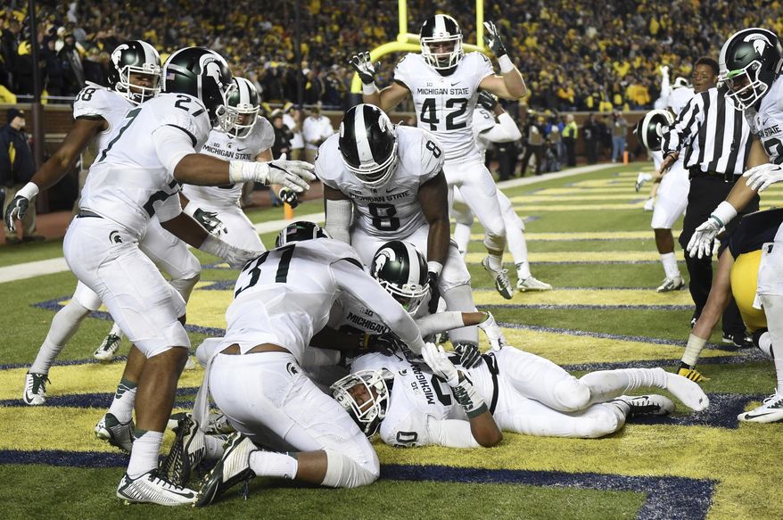 FILE - In this Saturday, Oct. 17, 2015 file photo, Michigan State defensive back Jalen Watts-Jackson (20) is surrounded by jubilant teammates after he recovered a fumbled snap on a punt in the closing seconds of the second half and returned it for a touchdown during an NCAA college football game against Michigan in Ann Arbor, Mich. Michigan State's last visit to the Big House ended with Michigan botching a punt and blowing a chance to beat the Spartans in a series they've controlled for nearly a decade. Michigan plays Michigan State on Saturday, Oct. 7, 2017. (Melanie Maxwell/The Ann Arbor News/MLive.com via AP, File)