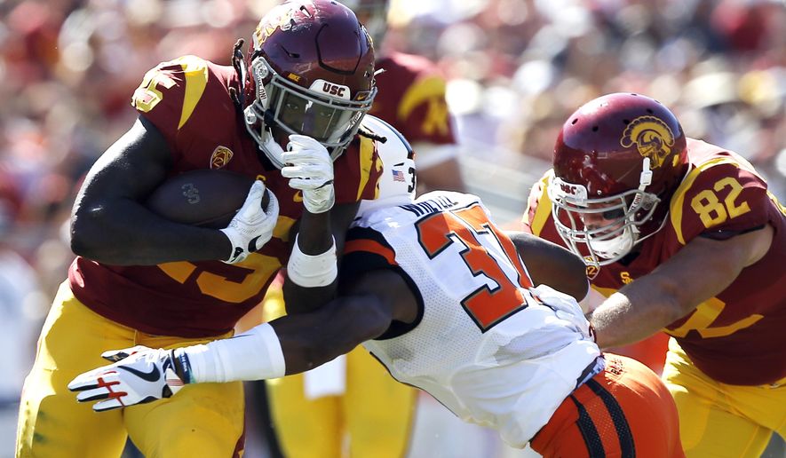Southern California running back Ronald Jones II, left, runs through Oregon State linebacker Kee Whetzel, center, with tight end Tyler Petite, right, blocking during the first half of an NCAA college football game in Los Angeles, Saturday, Oct. 7, 2017. (AP Photo/Alex Gallardo)