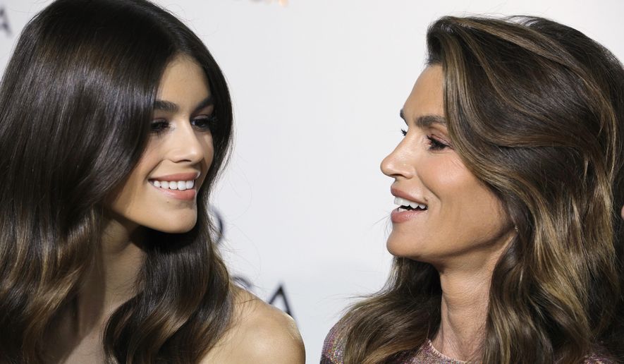 FILE - In this Sept. 29, 2017 file photo, model Cindy Crawford, right, poses with her daughter Kaia Gerber for photographers upon arrival at a party for Omega in Paris. Crawford says it’s inevitable that her 16-year-old daughter has followed her famous mother into the world of international modeling. Kaia Gerber made her New York Fashion Week debut last month. In an interview with The Associated Press, Crawford say she’s more concerned with her daughter getting her driver’s license than becoming a model.(AP Photo/Kamil Zihnioglu)