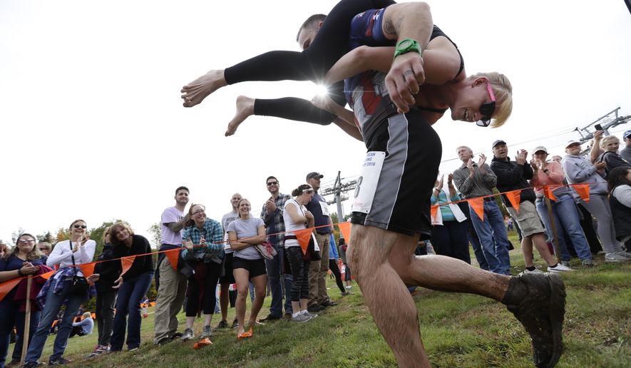 FILE - In this Oct. 8, 2016 file photo, Jaime Devine is carried by her husband, Thomas Devine, of Boston, Mass., during the North American Wife Carrying Championship at the Sunday River Ski Resort in Newry, Maine. Dozens of participants are vying for cash and beer in the North American Wife Carrying Championship. More than 60 couples are registered, and more are on a waiting list, for the annual event Saturday, Oct. 7, 2017 at the Sunday River in Maine.(AP Photo/Robert F. Bukaty, File)
