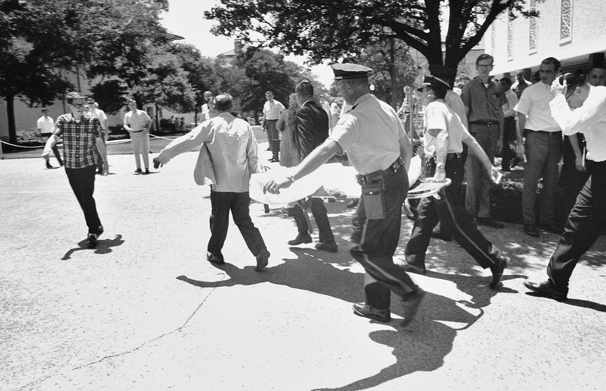 FILE - In this Aug. 1, 1966, file photo, one of the victims of Charles Joseph Whitman, the sniper who gunned down victims from a perch in the University of Texas tower, is carried across the campus to a waiting ambulance in Austin. Whitman, a 25-year-old architectural engineering major and ex-Marine, killed his wife, his mother and three others before climbing the 27 stories of a tower at the University of Texas and raining gunfire on the plaza below. Over 96 minutes, another 11 people were killed and 31 injured before Whitman was killed by police officers. (AP Photo/File)