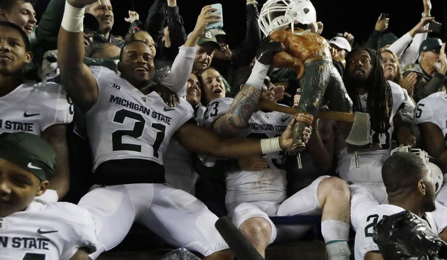 Michigan State players hold the Paul Bunyan statue after the team defeated Michigan 14-10 in an NCAA college football game, Saturday, Oct. 7, 2017, in Ann Arbor, Mich. (AP Photo/Carlos Osorio)
