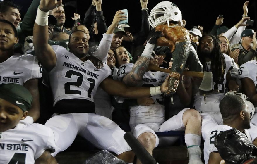 Michigan State players hold the Paul Bunyan statue after the team defeated Michigan 14-10 in an NCAA college football game, Saturday, Oct. 7, 2017, in Ann Arbor, Mich. (AP Photo/Carlos Osorio)