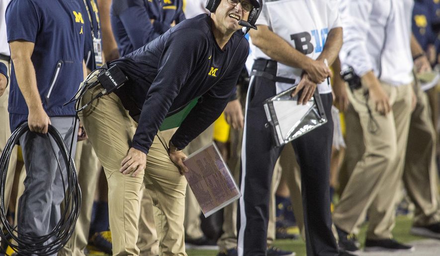 Michigan head coach Jim Harbaugh looks at the scoreboard along the sideline in the first quarter of an NCAA college football game against Michigan State in Ann Arbor, Mich., Saturday, Oct. 7, 2017. (AP Photo/Tony Ding)
