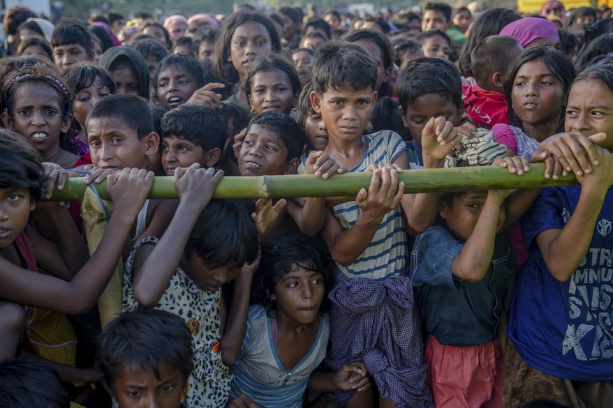 FILE - In this Sept. 25, 2017 file photo, Rohingya Muslim children, who crossed over from Myanmar into Bangladesh, wait to receive handouts near Balukhali refugee camp, Bangladesh. On Tuesday, Oct. 10, medical teams from the health ministry, supported by UNICEF and WHO, started a massive cholera immunization drive in the camps that accommodate the new arrivals as well as many of the hundreds of thousands of Rohingya who fled to Bangladesh during earlier spasms of violence in Myanmar, racing against time to prevent outbreaks of infectious diseases. (AP Photo/Dar Yasin, File)