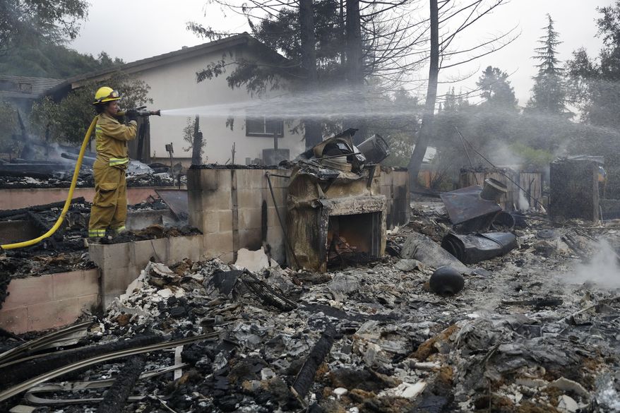 Napa City firefighter Hattie Borg hoses down a fire-ravaged home Monday, Oct. 9, 2017, in Napa, Calif. (AP Photo/Marcio Jose Sanchez)