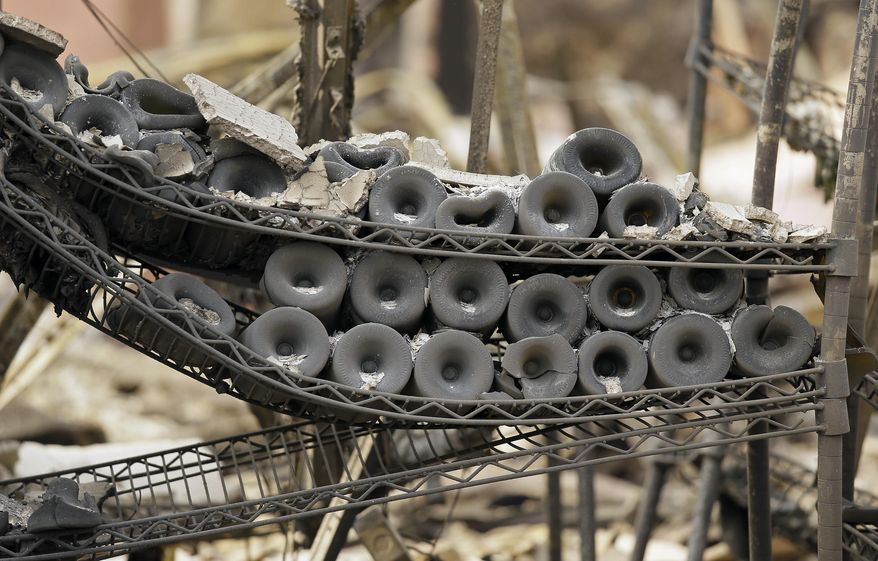 A rack of burned bottles of wine are seen at the Signorello Estate winery Tuesday, Oct. 10, 2017, in Napa, Calif. Worried California vintners surveyed the damage to their vineyards and wineries Tuesday after wildfires swept through several counties whose famous names have become synonymous with fine food and drink. (AP Photo/Eric Risberg)
