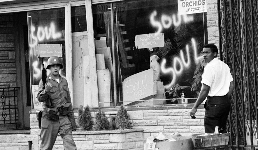 FILE - In this July 15, 1967 file photo a National Guard officer passes the smashed window of a black-owned flower shop in riot-torn Newark, N.J. The last surviving member of the Kerner Commission says he remains haunted that the panel's recommendations on US race relation and poverty were never adopted, but he is hopeful they will be one day. Former U.S. Sen. Fred Harris says 50 years after working on a report to examine the causes of the late 1960s race riots he strongly feels that poverty and structural racism still enflames racial tensions even as the United States becomes more diverse. (AP Photo,File)