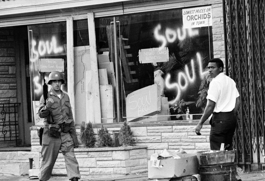 FILE - In this July 15, 1967 file photo a National Guard officer passes the smashed window of a black-owned flower shop in riot-torn Newark, N.J. The last surviving member of the Kerner Commission says he remains haunted that the panel's recommendations on US race relation and poverty were never adopted, but he is hopeful they will be one day. Former U.S. Sen. Fred Harris says 50 years after working on a report to examine the causes of the late 1960s race riots he strongly feels that poverty and structural racism still enflames racial tensions even as the United States becomes more diverse. (AP Photo,File)