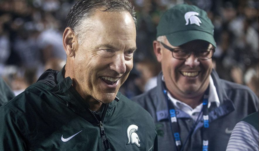 FILE - In this Saturday, Oct. 7, 2017, file photo, Michigan State head coach Mark Dantonio, left, celebrates with athletic director Mark Hollis, right, after the Spartans defeated Michigan 14-10 in an NCAA college football game in Ann Arbor, Mich. Michigan State returned to the Top 25 faster than many people expected. After beating Michigan last weekend, the No. 21 Spartans suddenly have to deal with something that's been mostly absent for the past year, expectations. (AP Photo/Tony Ding, File)