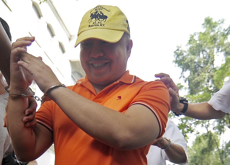 In this photo taken Aug. 14, 2017, Dr. Russell Salic is escorted in handcuffs for a preliminary investigation at the Department of Justice in Manila, Philippines. Dr. Salic, a Filipino doctor accused by U.S. authorities of plotting attacks in New York City denies that he helped finance the disrupted plot and will fight a U.S. extradition request, his lawyer told The Associated Press on Tuesday, Oct. 10, 2017. (AP Photo)