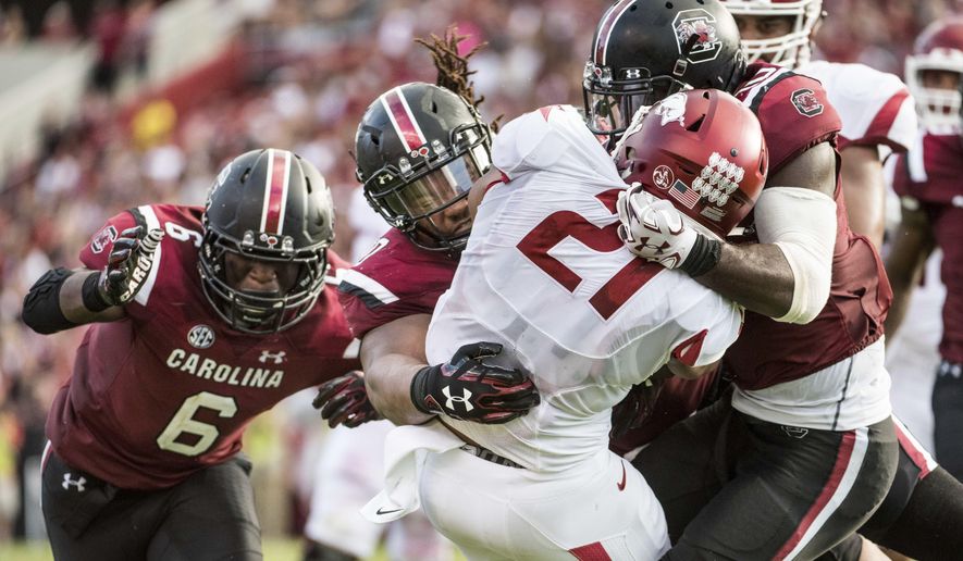 FILE - In this Oct. 7, 2017, file photo, Arkansas running back Devwah Whaley (21) is tackled by South Carolina linebacker Skai Moore (10), Dante Sawyer, center, and T.J. Brunson (6) during the first half of an NCAA college football game, in Columbia, S.C. South Carolina's defense turned a tight game into a blowout with three second-half scores. It's the latest evidence of a defensive turnaround for the Gamecocks and coach Will Muschamp after a struggling debut a season ago. (AP Photo/Sean Rayford, File)