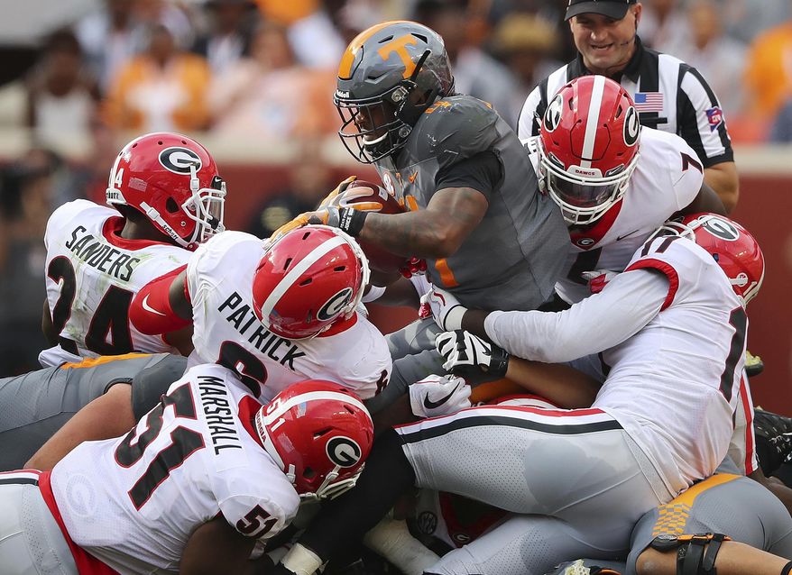 FILE - In this Sept. 30, 2017, file photo, Georgia defenders David Marshall (51), Natrez Patrick (6), Dominick Sanders (24), Lorenzo Carter (7) and Davin Bellamy (17) gang tackle Tennessee running back John Kelly at the line of scrimmage for no gain during the first half of an NCAA college football game in Knoxville, Tenn. The one thing Alabama, Georgia and Auburn do well week in and week out, is play defense. Their defensive squads are among the best in the country, and it has them poised to make a run at the College Football Playoffs. (Curtis Compton/Atlanta Journal-Constitution via AP, File)
