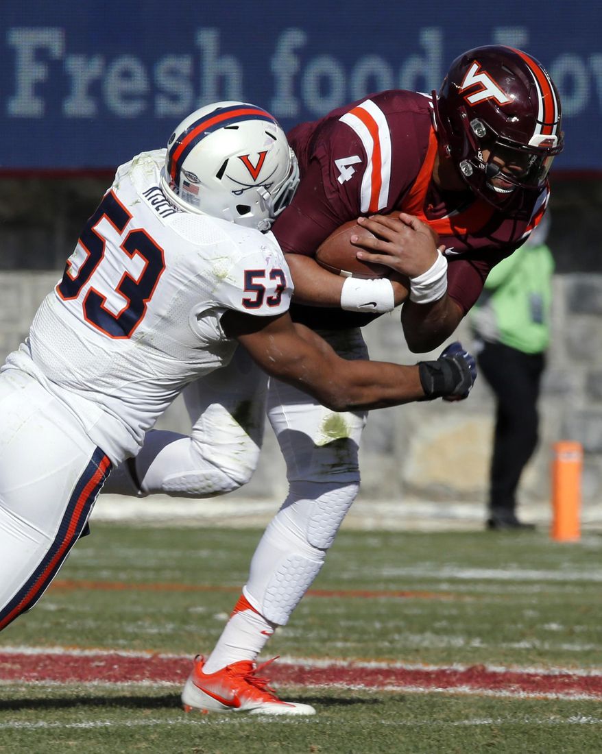 FILE - In this Nov. 26, 2016, file photo, Virginia linebacker Micah Kiser (53) wraps up Virginia Tech quarterback Jerod Evans (4) during the first half of an NCAA college football game in Blacksburg, Va. Kiser is the anchor for a Cavaliers defense heading south to play North Carolina. (AP Photo/Steve Helber, File)
