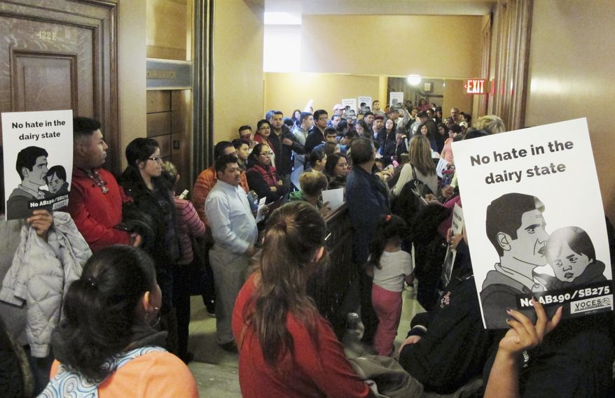 A crowd of opponents to a bill in the Wisconsin Legislature that would outlaw "sanctuary cities" fills the hallway outside of a hearing room Thursday, Oct. 12, 2017, in Madison, Wis. (AP Photo/Scott Bauer)
