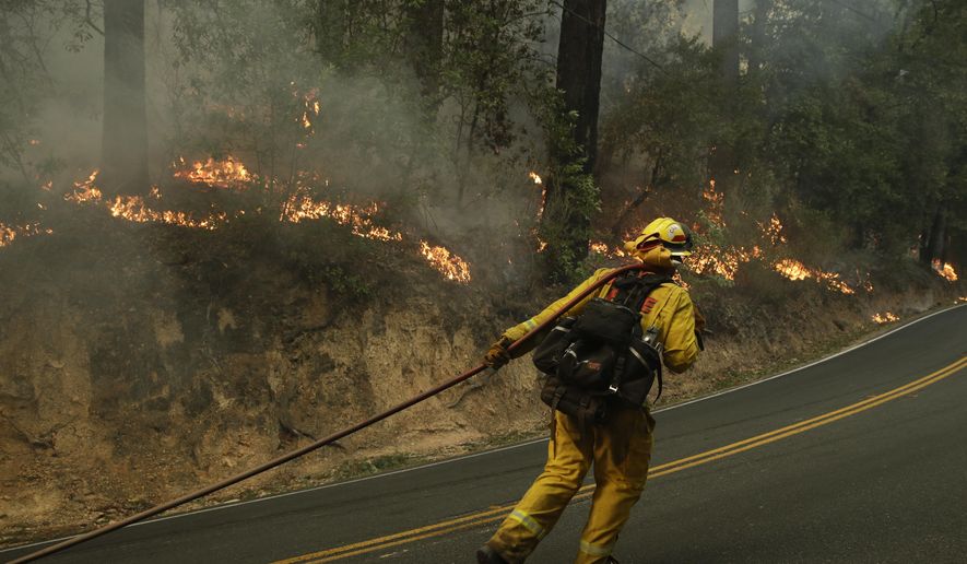 Firefighter David Allhiser carries a water hose to put out a fire Thursday, Oct. 12, 2017, near Calistoga, Calif. Officials say progress is being made in some of the largest wildfires burning in Northern California but that the death toll is almost sure to surge. (AP Photo/Jae C. Hong)