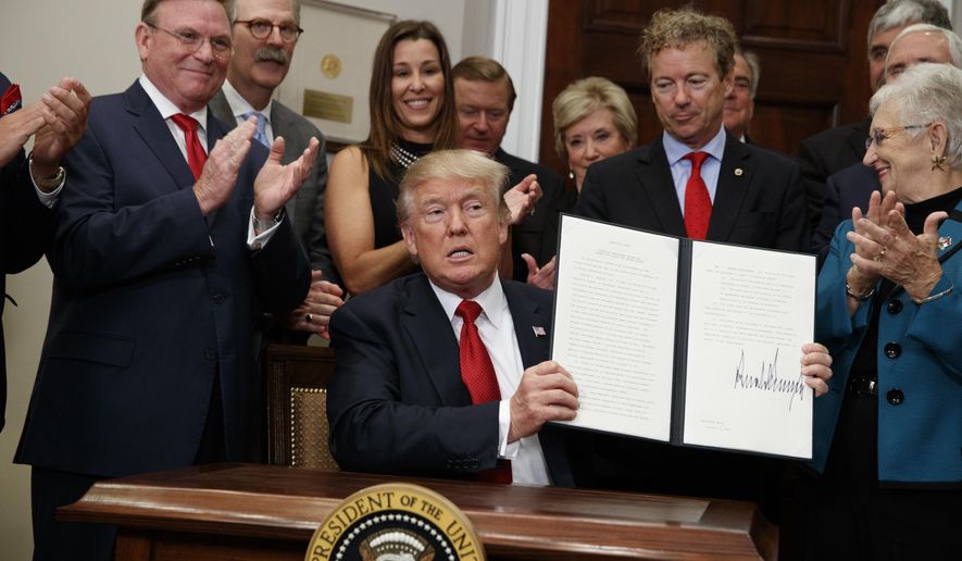 FILE - In this Oct. 12, 2017, photo, President Donald Trump shows an executive order on health care that he signed in the Roosevelt Room of the White House, in Washington. Trump presented a distorted picture of his tax plan this past week and claimed he was trying to keep the Obama health law’s insurance markets afloat even as he took steps that could well sink them. (AP Photo/Evan Vucci, File)