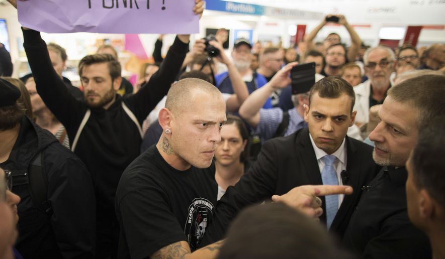 In this Oct. 14, 2017 photo protesters scuffle with stewards during a reading and discussion with Bjoern Hoecke, the head of the nationalist AfD's faction in the Thuringia state legislature at the the Frankfurt Book Fair in Frankfurt am Main, Germany. (Frank Rumpenhorst/dpa via AP)