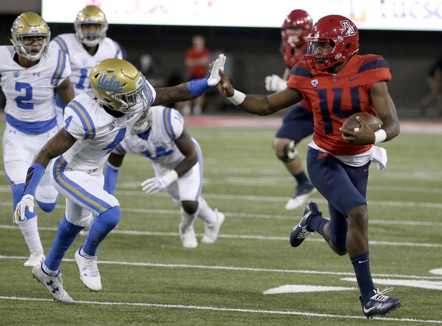 Arizona quarterback Khalil Tate (14) stiff arms UCLA defensive back Jaleel Wadood (4) and scores a touchdown in the first half during an NCAA college football game, Saturday, Oct. 14, 2017, in Tucson, Ariz. (AP Photo/Rick Scuteri)
