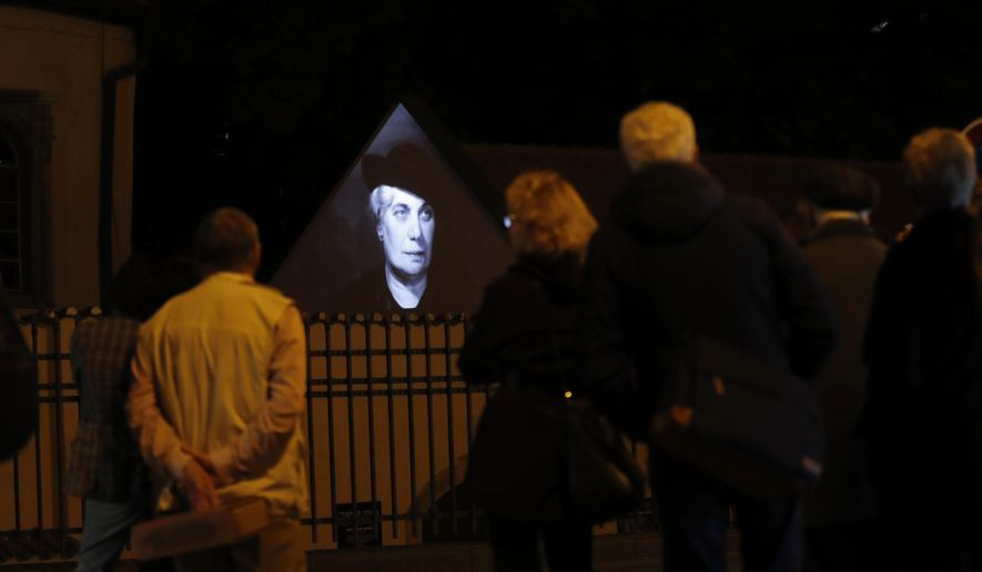 People watch as photographs of Czech Jews who were killed by the Nazis during World War II are projected on the outer wall of a Jewish bath at the Pinkas Synagogue in Prague, Czech Republic, Monday, Oct. 16, 2017. (AP Photo/Petr David Josek)