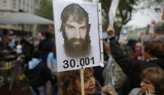 CORRECTS TO REMOVE POLICE DETAINED MALDONADO - FILE - In this Oct. 1, 2017 file photo, a woman holds a photo of Santiago Maldonado during a demonstration at Plaza de Mayo in Buenos Aires, Argentina. Investigators believe that a body found Tuesday, Oct. 17, 2017, during a rake of a river in Patagonia is that of Maldonado, who went missing two months ago after Argentine border police clashed during an operation against Mapuche Indians who were blocking a highway in Argentina&#39;s Patagonia. (AP Photo/Victor R. Caivano, File)