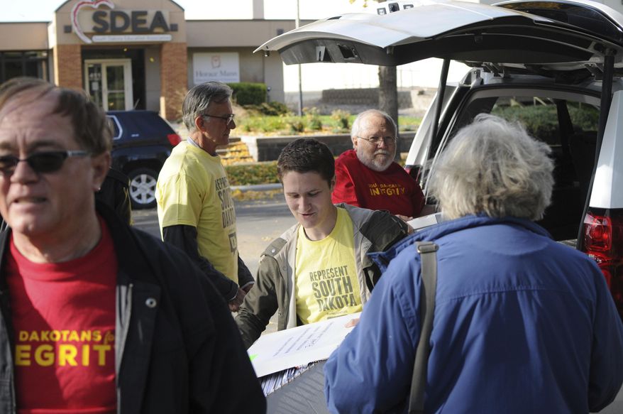 Represent South Dakota spokesman Doug Kronaizl, center, and other supporters of a proposed government ethics constitutional amendment unload boxes of petitions outside the state Capitol in Pierre, S.D., Wednesday, Oct. 18, 2017. The campaign says it turned in more than 50,000 signatures to the Secretary of State's office to put the measure on the 2018 ballot. (AP Photo/James Nord)