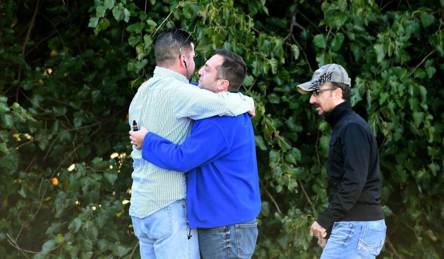 Unidentified bystanders embrace as police and Emergency Medical Services respond to a shooting at a business park in the Edgewood area of Harford County, Md., Wednesday, Oct. 8, 2017. (Matt Button/The Baltimore Sun via AP)