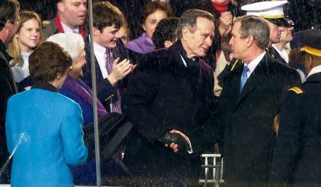 President George W. Bush is congratulated by his father, former President George H.W. Bush, as he enters the reviewing stand in front of the White House after his inauguration on Jan. 20, 2001. (The Washington Times)