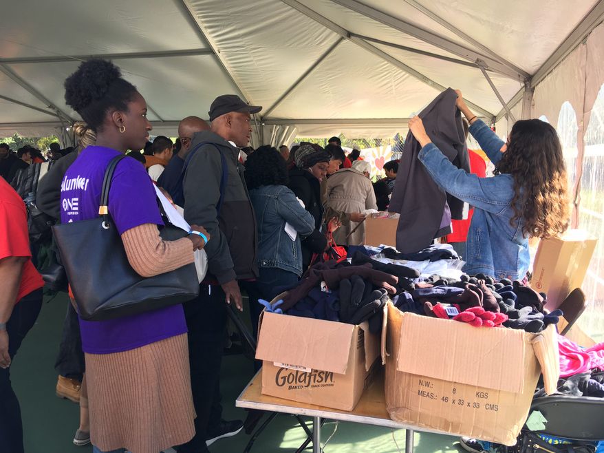 A volunteer with Project Homeless Connect holds up a jacket to give to a homeless man at the event, which connects the homeless population to services in the District at the Kennedy Recreation Center on Thursday. About 500 attended the event. (Laura Kelly/The Washington Times)