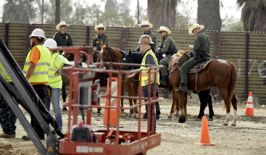 Border Patrol agents on horseback look on as crews work on border wall prototypes Thursday, Oct. 19, 2017, in San Diego. Companies are nearing an Oct. 26 deadline to finish building eight prototypes of President Donald Trump&#39;s proposed border wall with Mexico. (AP Photo/Gregory Bull)
