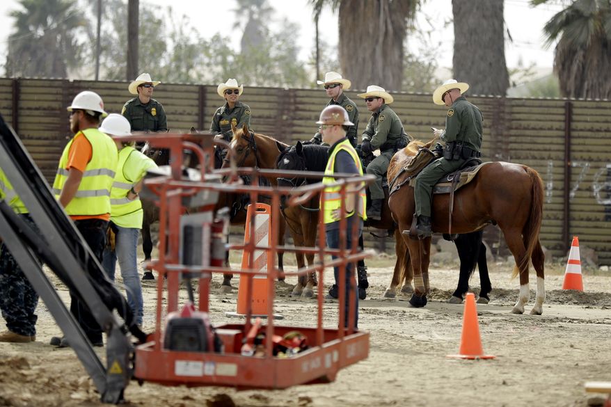 Border Patrol agents on horseback look on as crews work on border wall prototypes Thursday, Oct. 19, 2017, in San Diego. Companies are nearing an Oct. 26 deadline to finish building eight prototypes of President Donald Trump's proposed border wall with Mexico. (AP Photo/Gregory Bull)