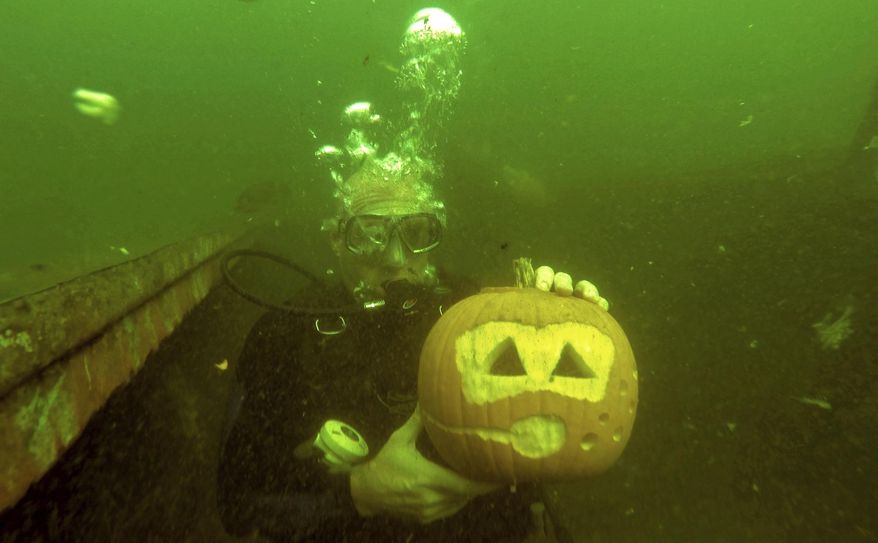 In this Sunday, Oct 15, 2017, photo, Scuba Diver, Matt Williamson, of Etlderton, shows off his Jack-O'-Lantern with a Scuba theme during his under water pumpkin carving experience at Crusy's Quarry, in Slippery Rock, Pa. Scott's Scuba owner Scott Camerlo said the challenges of carving a pumpkin about 20 feet underwater are their buoyancy and lessened gravity. (Louis B. Ruediger /Pittsburgh Tribune-Review via AP)