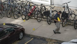 An investigator marks evidence while working the scene of an early morning homicide Thursday,, Oct. 19, 2017, in Fort Collins, Colo. The fatal shooting took place outside a housing complex about a mile west of Colorado State University. (Timothy Hurst /The Coloradoan via AP)